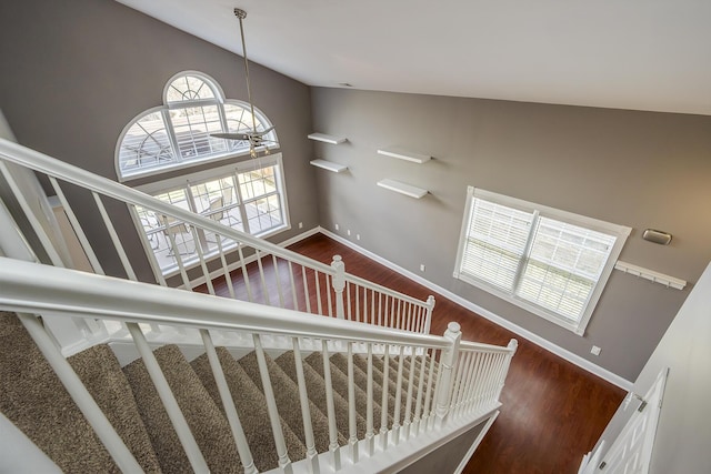 stairway featuring lofted ceiling, wood finished floors, and baseboards