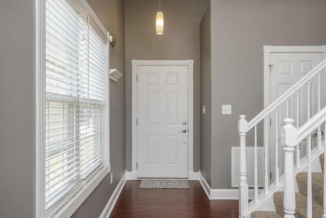 foyer entrance with visible vents, stairway, dark wood-type flooring, and baseboards