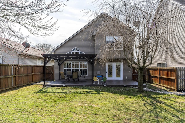 back of property with a yard, a wooden deck, and a fenced backyard