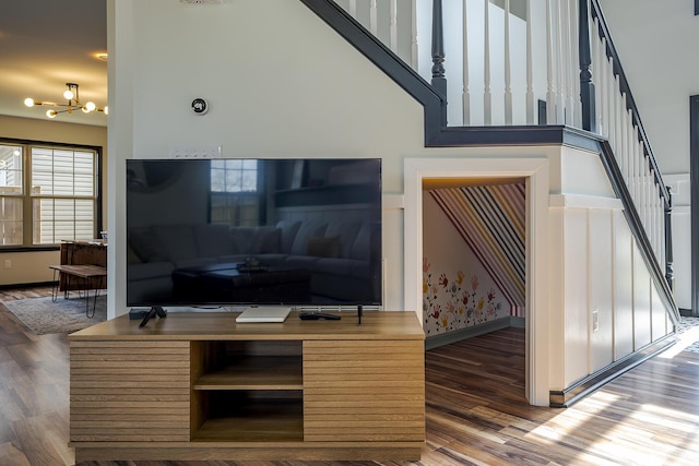 living area with a chandelier, stairway, baseboards, and wood finished floors