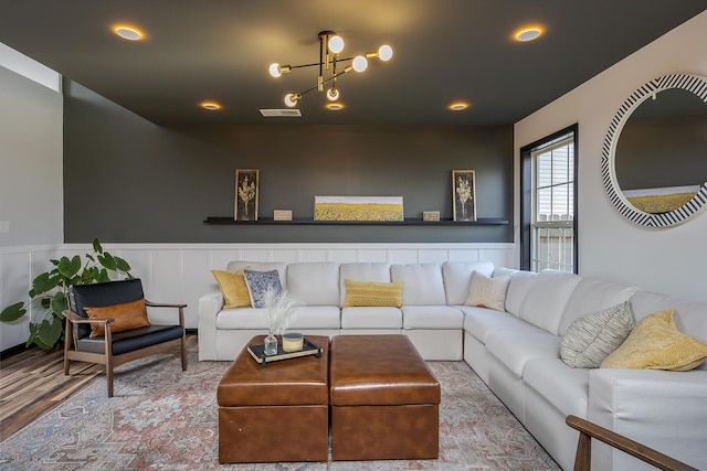 living area with a notable chandelier, wainscoting, visible vents, and wood finished floors