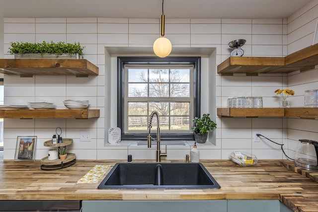 kitchen with a sink, open shelves, tasteful backsplash, and wood counters