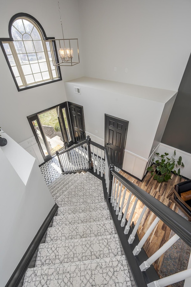 stairway with a notable chandelier, a high ceiling, and visible vents