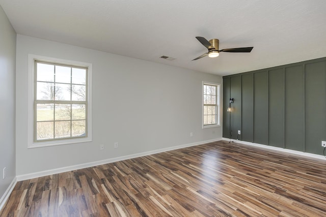 empty room featuring wood finished floors, a ceiling fan, visible vents, baseboards, and a textured ceiling