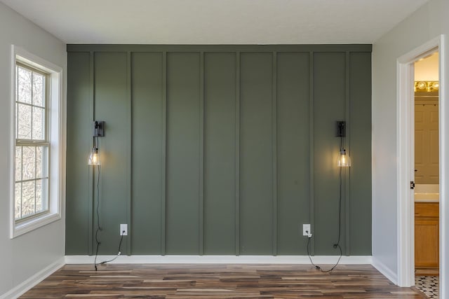 interior space featuring baseboards, dark wood finished floors, and a decorative wall