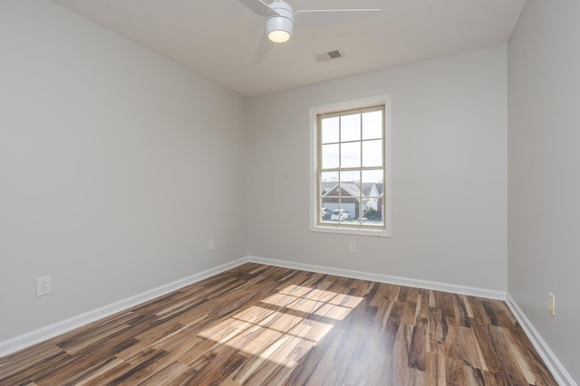 empty room with a ceiling fan, wood finished floors, visible vents, and baseboards