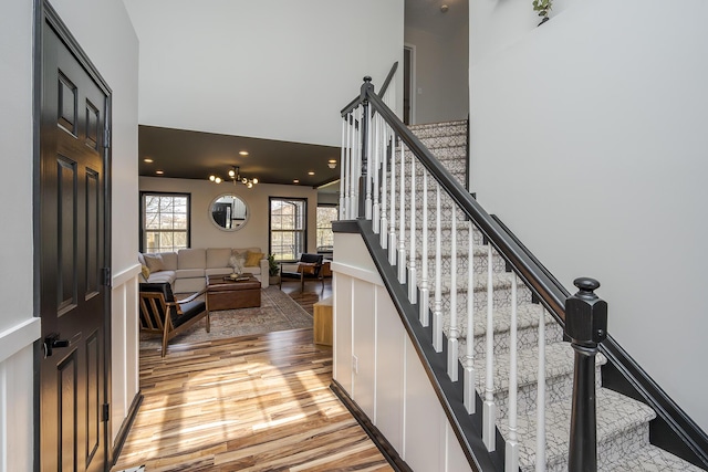 stairway with a high ceiling, recessed lighting, and wood finished floors