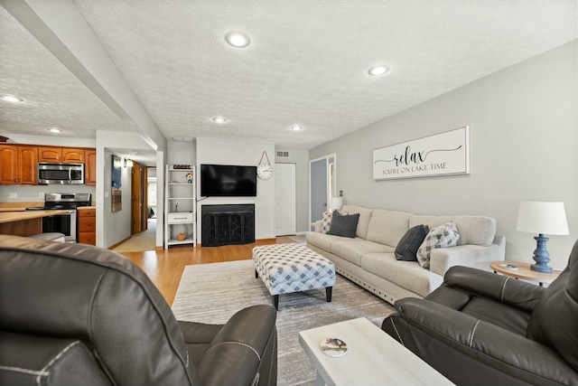 living area featuring recessed lighting, light wood-style floors, and a textured ceiling