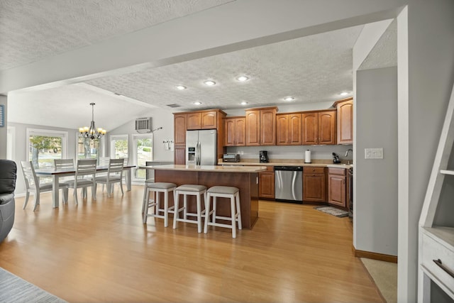 kitchen featuring a kitchen island, stainless steel appliances, light countertops, a kitchen bar, and a chandelier