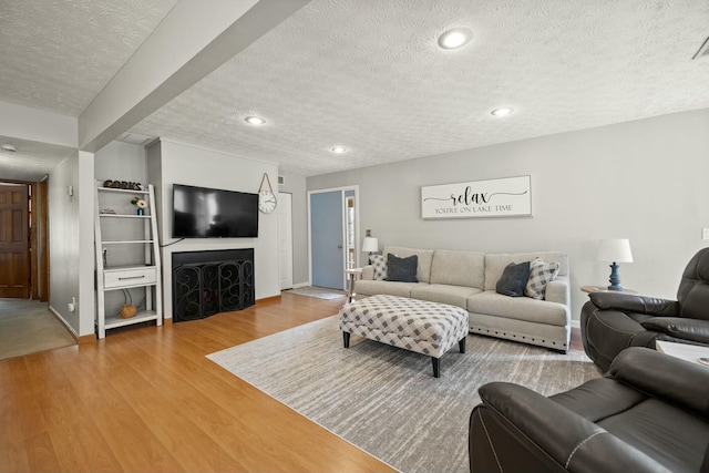 living room with recessed lighting, a textured ceiling, baseboards, and wood finished floors