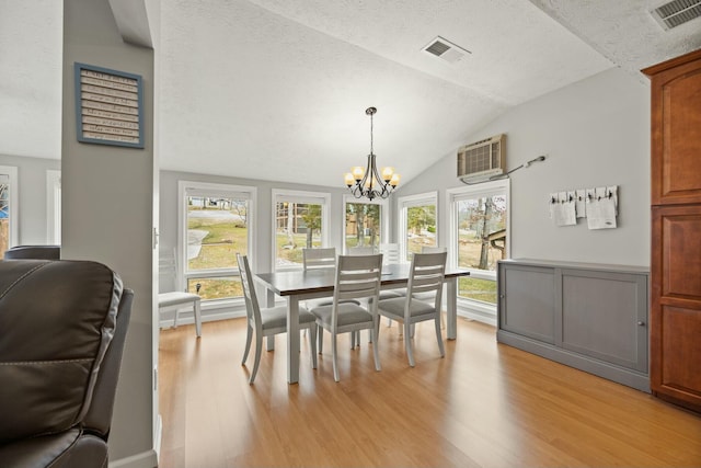 dining room featuring visible vents, lofted ceiling, a notable chandelier, and light wood finished floors