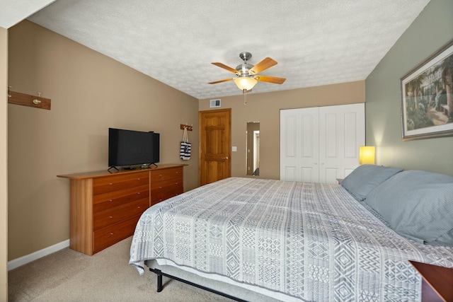 bedroom with a ceiling fan, baseboards, a closet, a textured ceiling, and light colored carpet