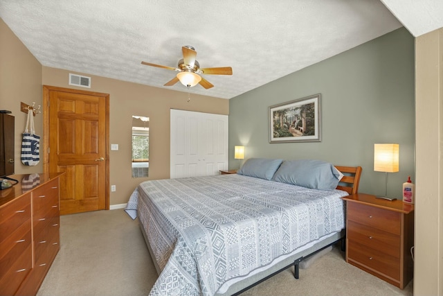 bedroom with light colored carpet, visible vents, a closet, and a textured ceiling