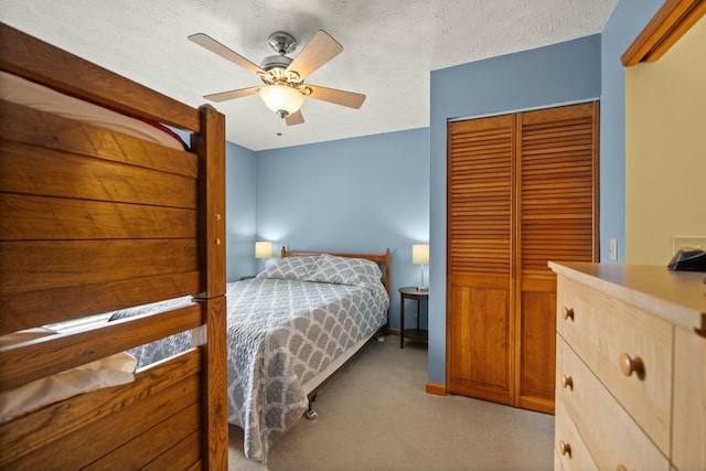 bedroom with a closet, light colored carpet, a ceiling fan, and a textured ceiling