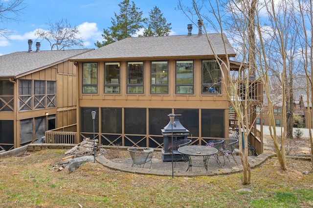 rear view of property featuring a patio, roof with shingles, and stairs