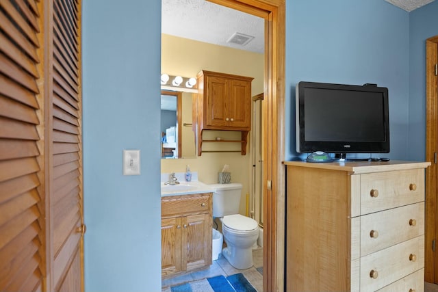 bathroom featuring tile patterned floors, toilet, visible vents, and a textured ceiling