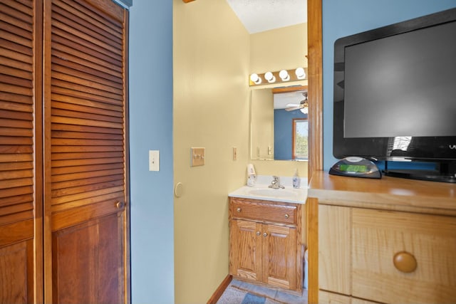 bathroom with vanity, baseboards, a closet, and ceiling fan