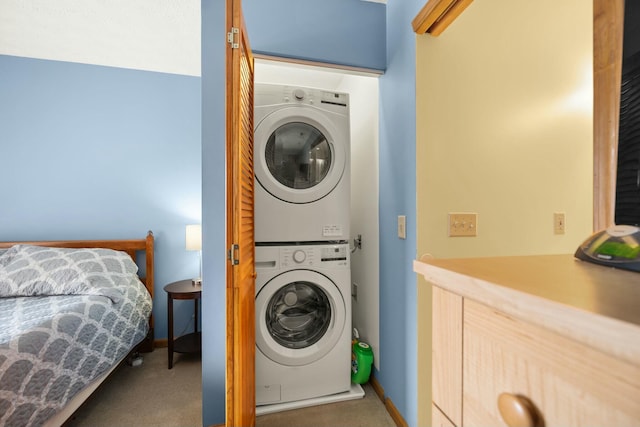 laundry room featuring laundry area, stacked washer and dryer, carpet, and baseboards