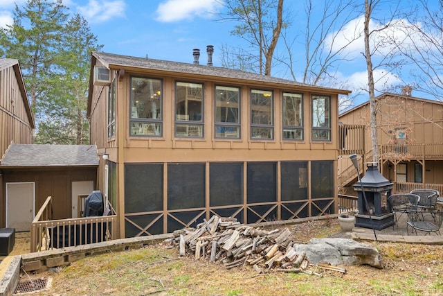 rear view of house featuring roof with shingles and a wall unit AC