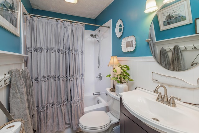 bathroom featuring toilet, vanity, shower / bath combo, wainscoting, and a textured ceiling