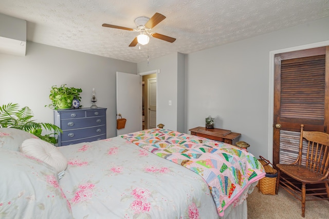 carpeted bedroom featuring ceiling fan and a textured ceiling