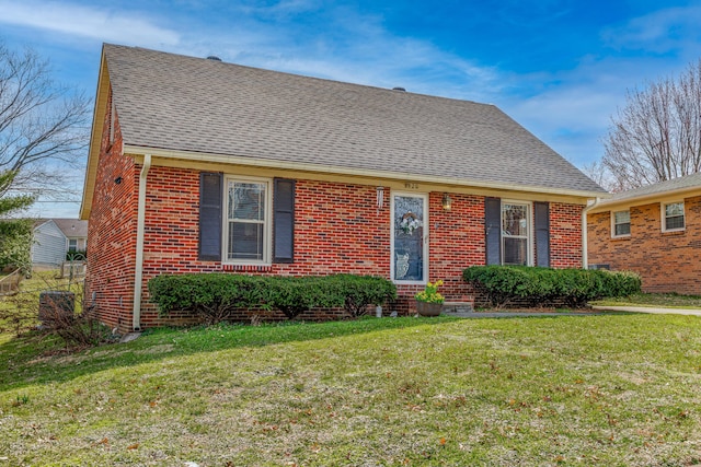 view of front facade with a front yard, brick siding, and a shingled roof