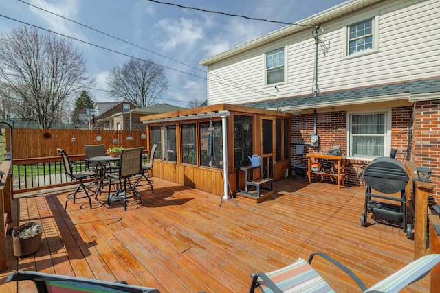 wooden terrace featuring outdoor dining space, fence, and a sunroom