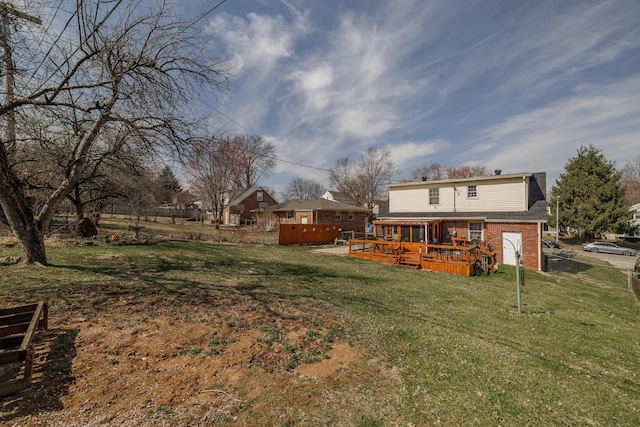 back of house with a deck, a yard, and brick siding