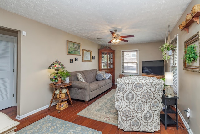 living area with a textured ceiling, wood finished floors, baseboards, and ceiling fan