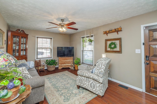 living room with visible vents, a ceiling fan, a textured ceiling, wood finished floors, and baseboards