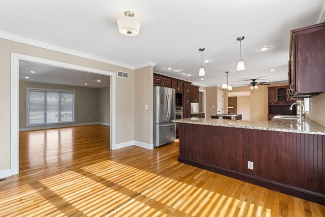 kitchen featuring a peninsula, ornamental molding, light wood finished floors, and freestanding refrigerator