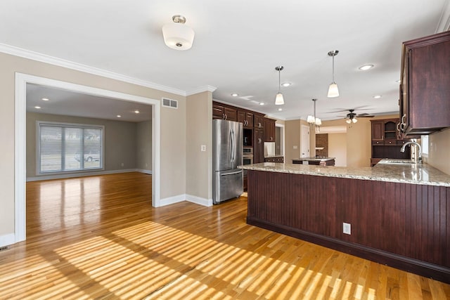 kitchen with crown molding, ceiling fan, light wood-type flooring, a peninsula, and freestanding refrigerator