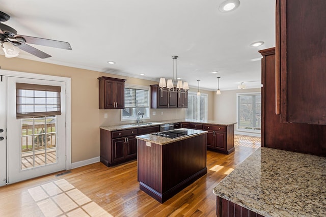 kitchen with visible vents, a kitchen island, a peninsula, a sink, and crown molding