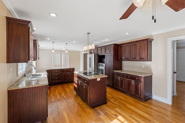 kitchen featuring a kitchen island, ornamental molding, appliances with stainless steel finishes, light wood-style floors, and a sink