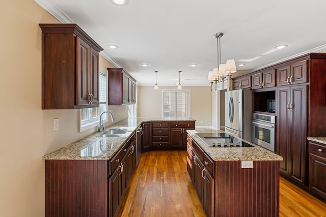 kitchen with a sink, light wood-type flooring, pendant lighting, stainless steel appliances, and a peninsula
