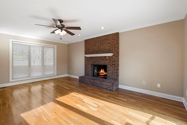 unfurnished living room featuring crown molding, baseboards, ceiling fan, a fireplace, and wood finished floors