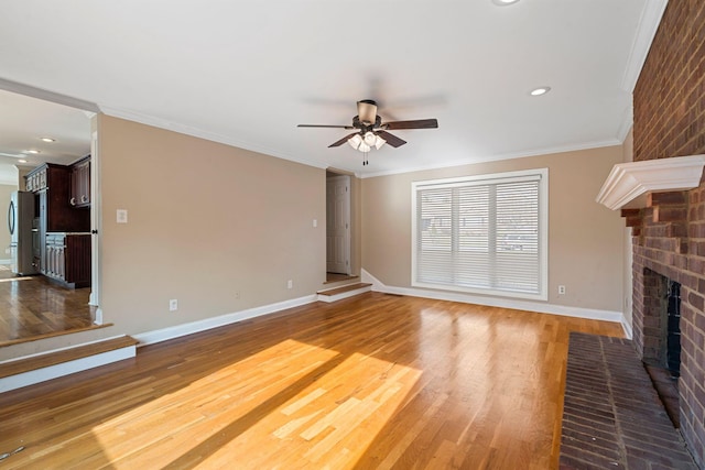 unfurnished living room with wood finished floors, baseboards, a fireplace, ornamental molding, and ceiling fan