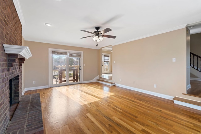 unfurnished living room with crown molding, a brick fireplace, wood finished floors, and ceiling fan