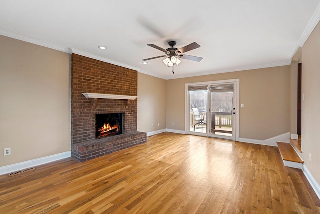 unfurnished living room with wood finished floors, baseboards, visible vents, a fireplace, and ornamental molding