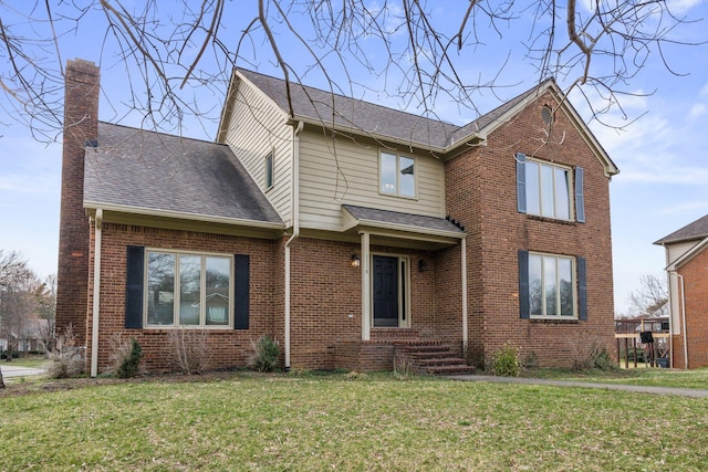 traditional-style house featuring a shingled roof, a front yard, brick siding, and a chimney