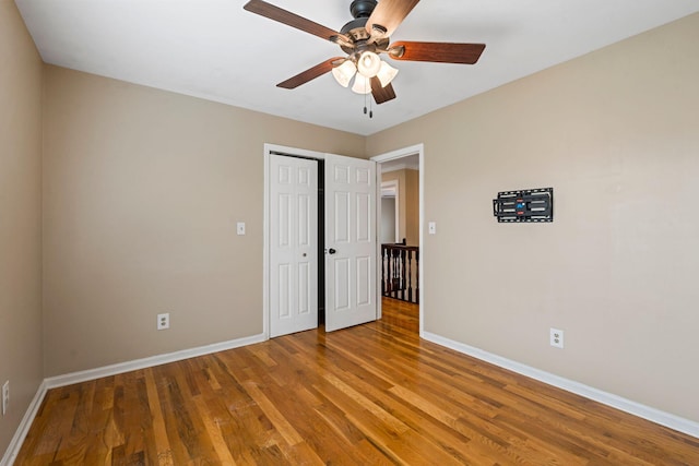 unfurnished bedroom with a closet, ceiling fan, baseboards, and wood finished floors