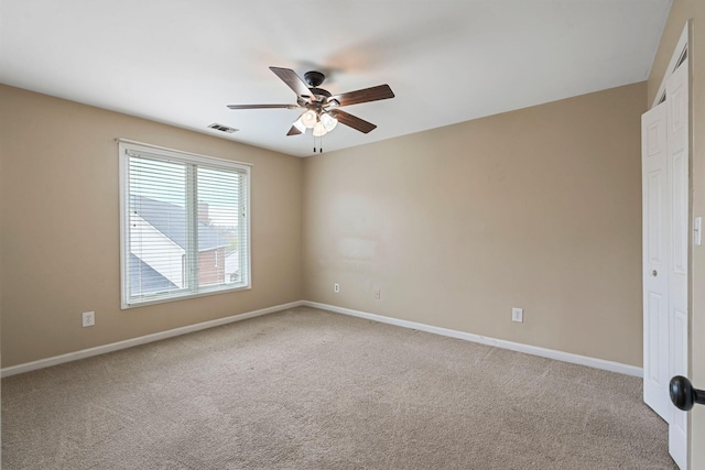 empty room featuring a ceiling fan, carpet, visible vents, and baseboards