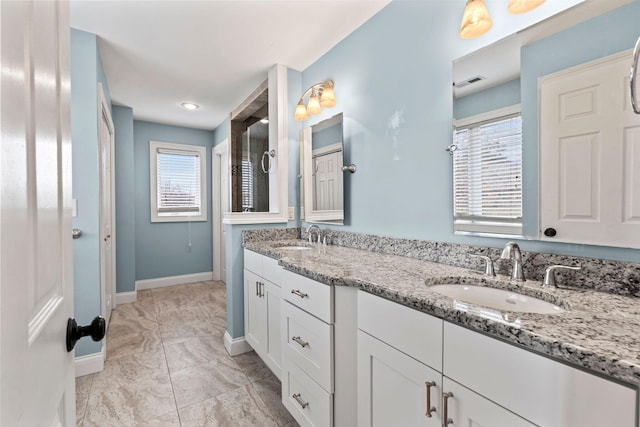 bathroom with baseboards, a sink, visible vents, and double vanity