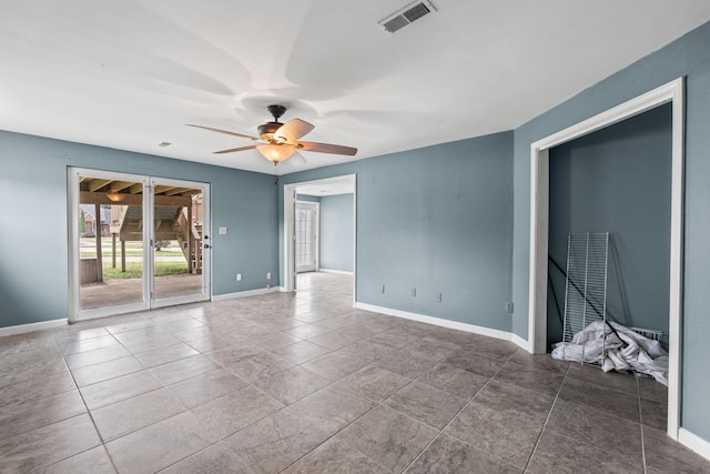 empty room with tile patterned floors, visible vents, baseboards, and ceiling fan