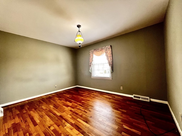 unfurnished room featuring visible vents, baseboards, and wood finished floors