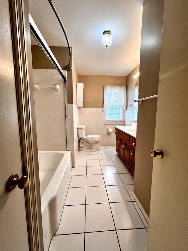 full bathroom with a wainscoted wall, toilet, tile walls, tile patterned flooring, and vanity