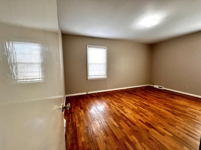 spare room featuring hardwood / wood-style flooring and baseboards