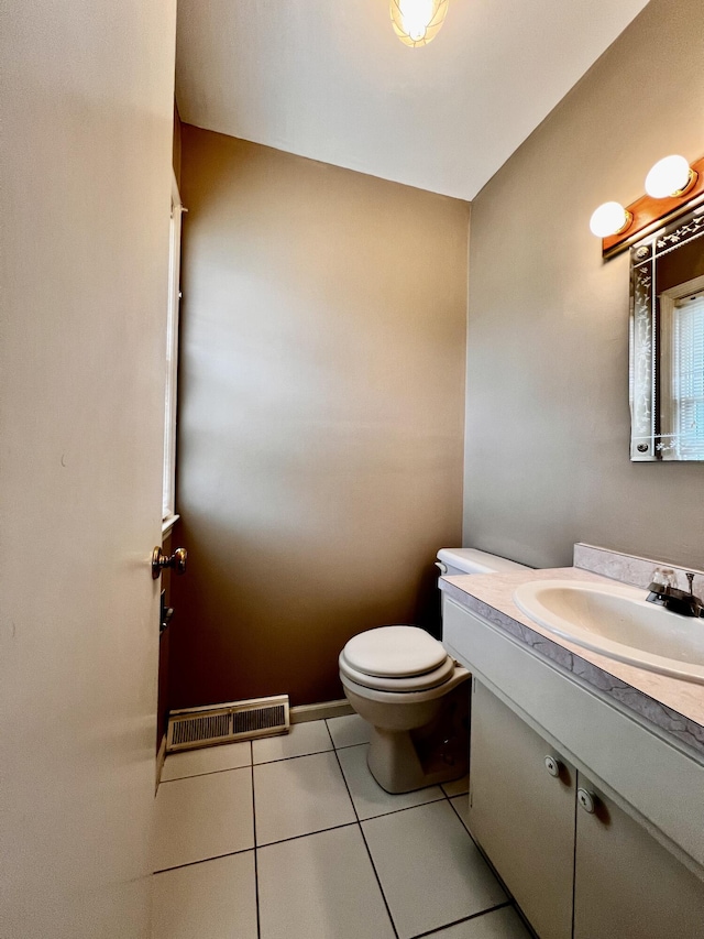 half bath featuring tile patterned floors, visible vents, toilet, baseboards, and vanity