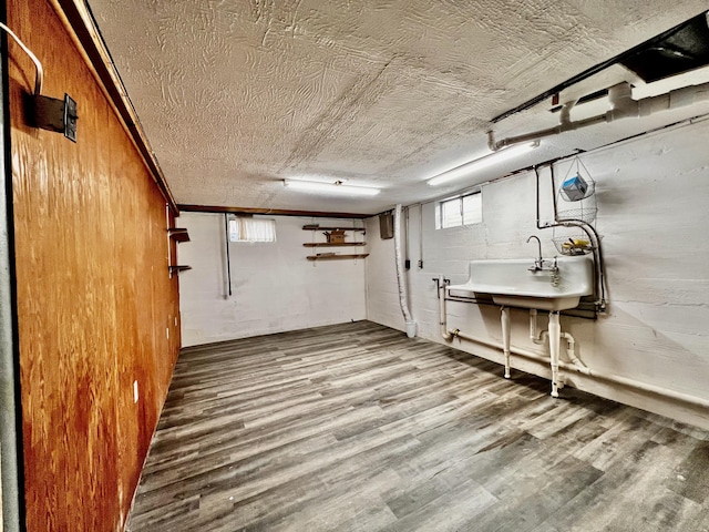 basement with a textured ceiling, wood finished floors, and concrete block wall