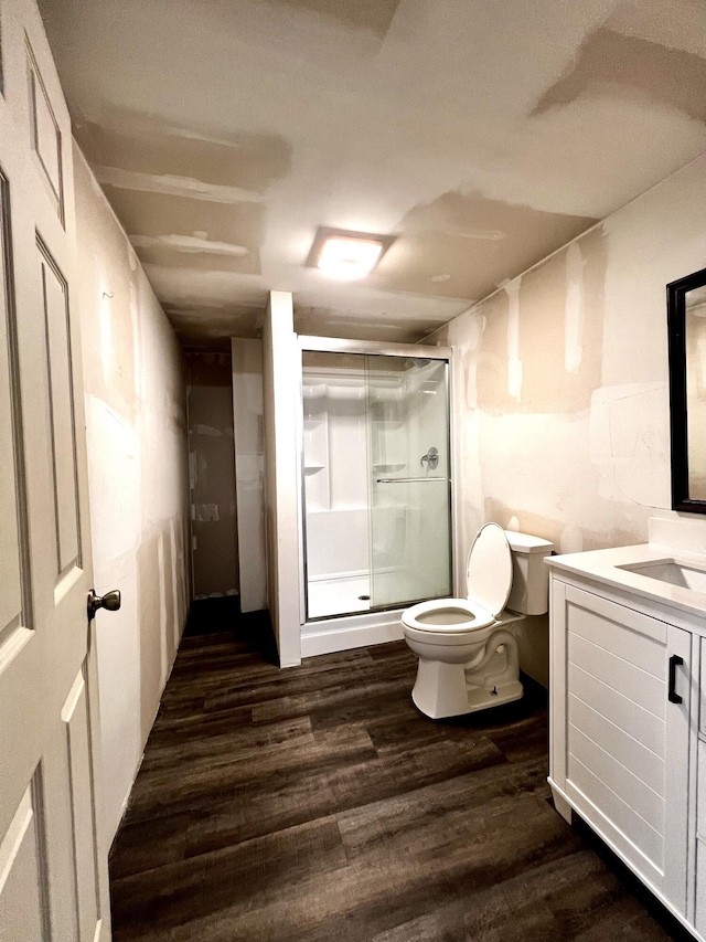 full bathroom with a stall shower, toilet, vanity, and wood finished floors